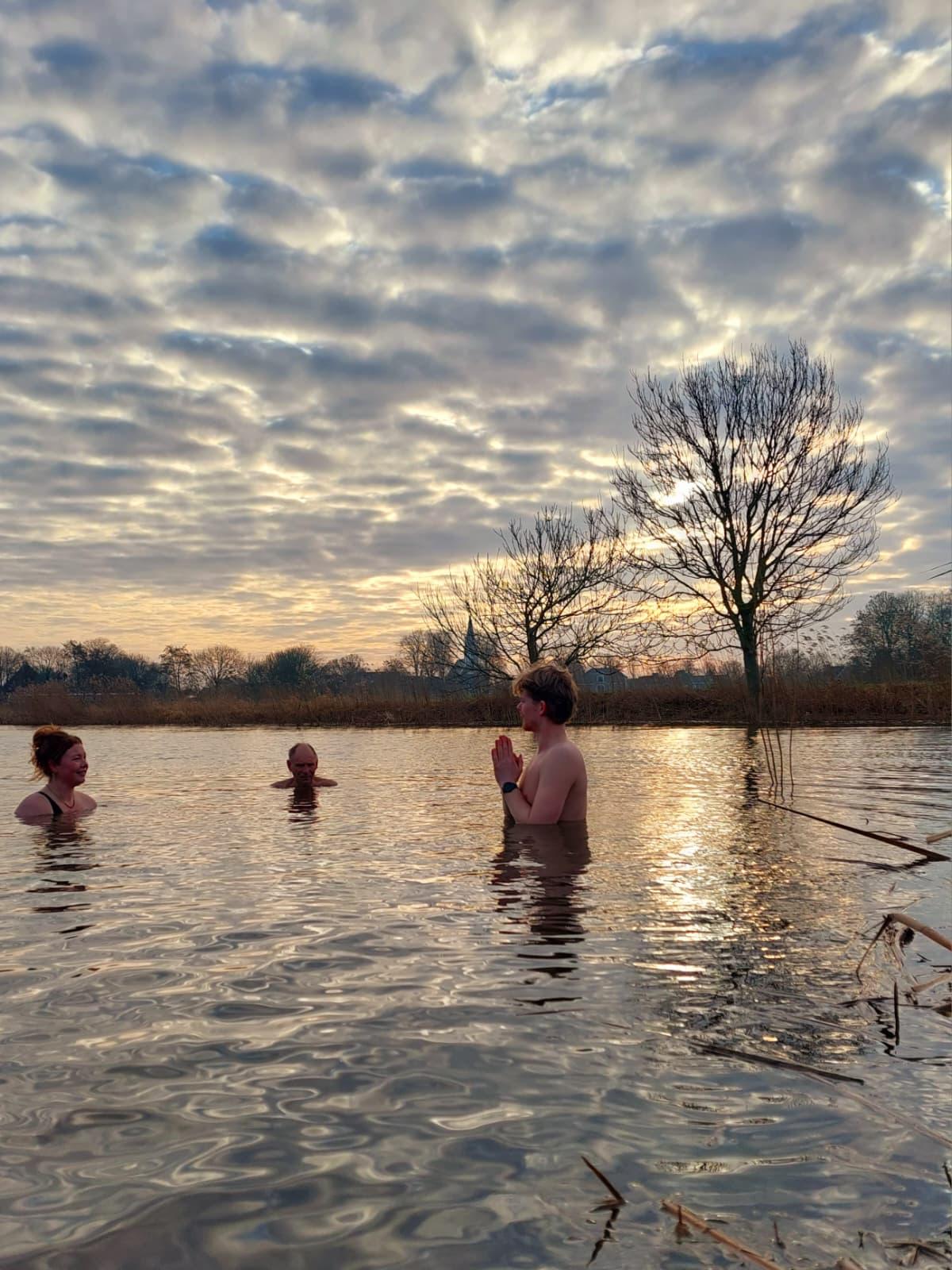 Deelnemers in het koude water tijdens een Leefsterk sessie bij zonsondergang